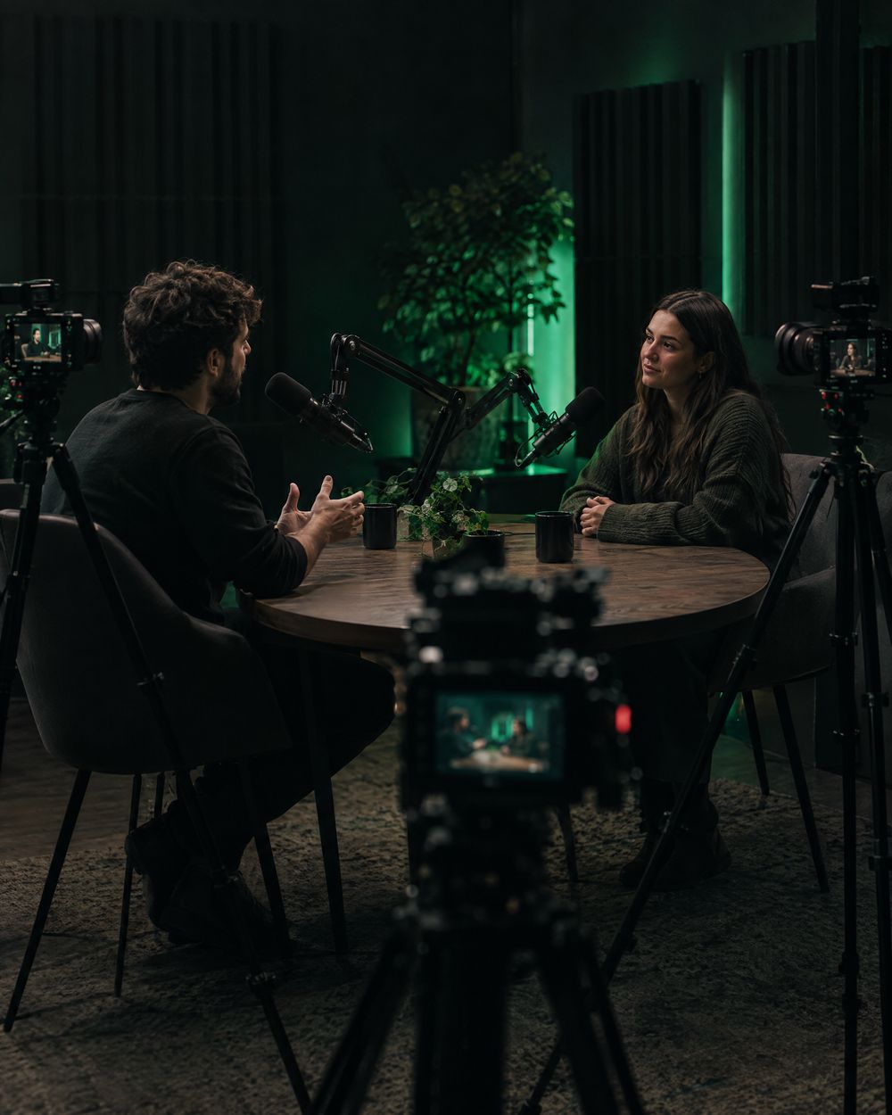 A podcast studio, two people at the table with microphones